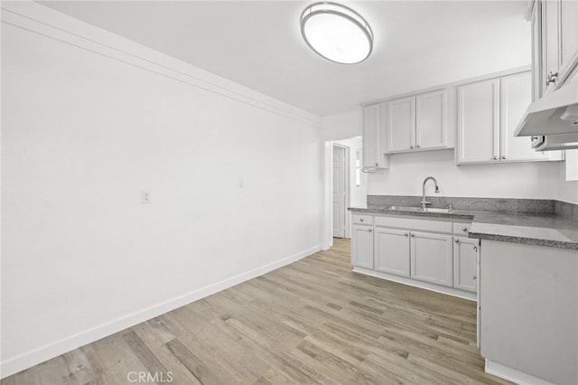 kitchen with sink, white cabinetry, crown molding, and light hardwood / wood-style flooring