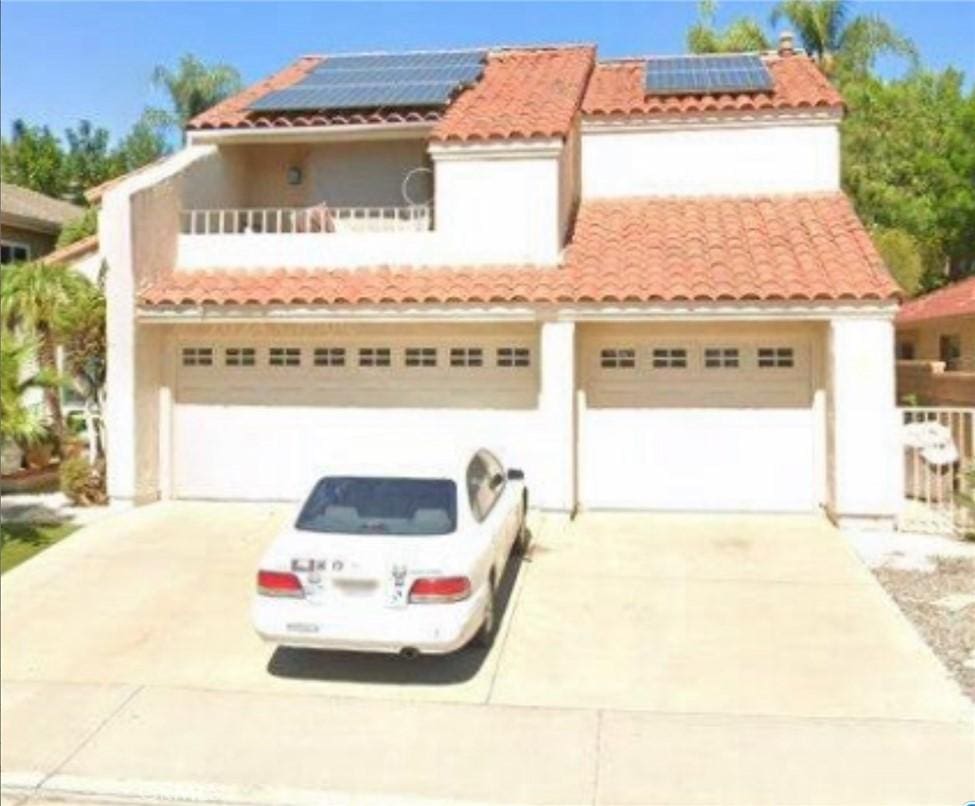 mediterranean / spanish home with solar panels, a balcony, and a garage