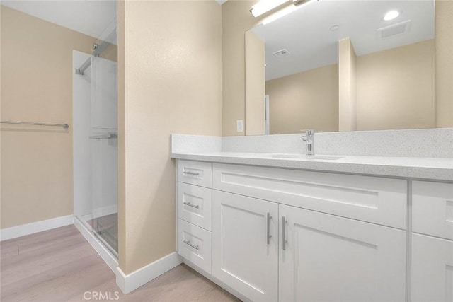 bathroom featuring wood-type flooring, vanity, and a shower with shower door