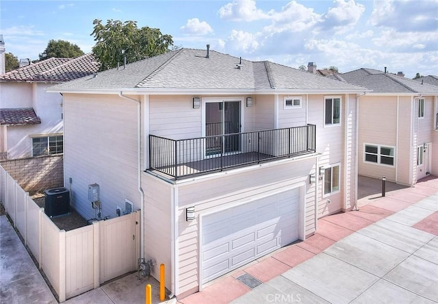 rear view of house featuring a balcony, a garage, and central air condition unit