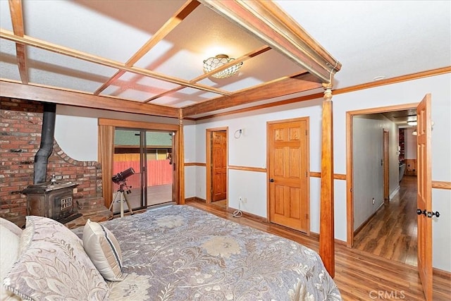 bedroom with hardwood / wood-style floors, a wood stove, and crown molding