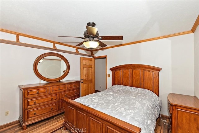 bedroom with ceiling fan, ornamental molding, and dark wood-type flooring