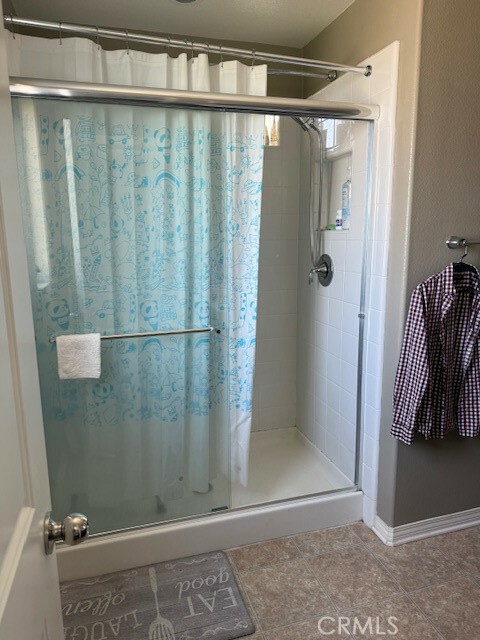 bathroom featuring a shower with door and tile patterned flooring