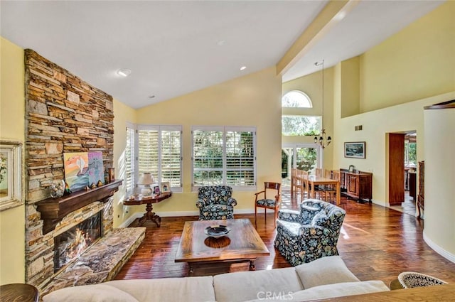 living room with dark hardwood / wood-style flooring, high vaulted ceiling, a stone fireplace, and a healthy amount of sunlight