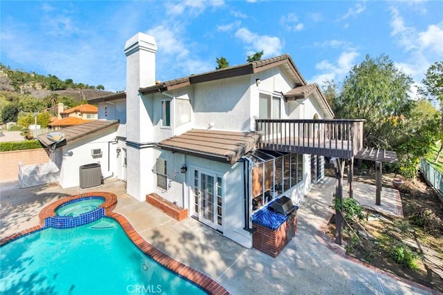 back of property featuring a swimming pool with hot tub, cooling unit, a patio, and french doors