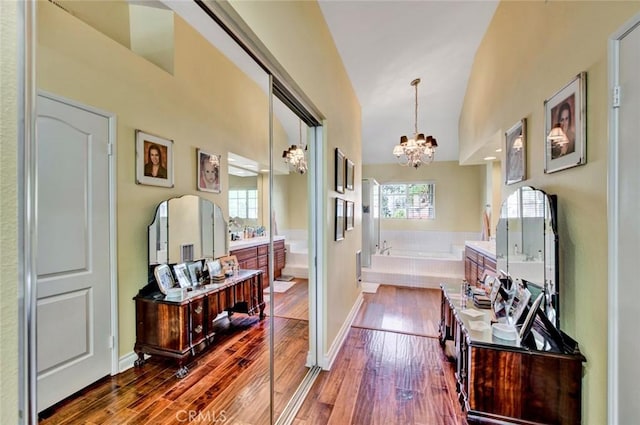 hallway featuring dark hardwood / wood-style flooring, high vaulted ceiling, a healthy amount of sunlight, and a notable chandelier