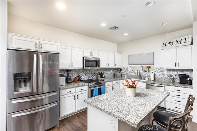 kitchen featuring dark hardwood / wood-style flooring, stainless steel appliances, a kitchen island, and white cabinetry