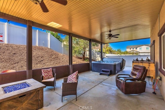 view of patio with a fire pit, ceiling fan, and a hot tub