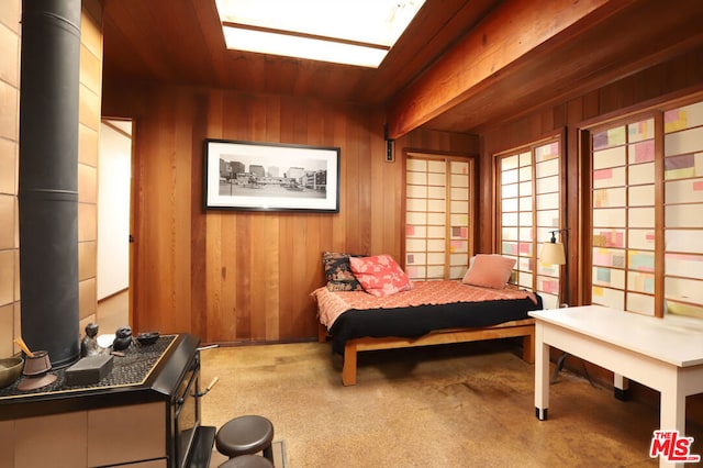 bedroom featuring beam ceiling, wooden walls, and wood ceiling