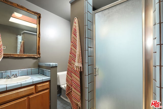 bathroom featuring tile patterned flooring, vanity, an enclosed shower, and toilet