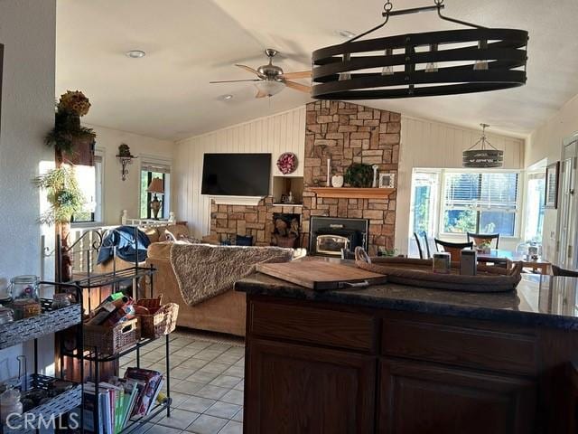 kitchen featuring lofted ceiling with beams, a stone fireplace, and plenty of natural light