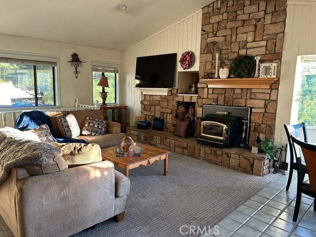 living room featuring tile patterned floors, a wood stove, and vaulted ceiling