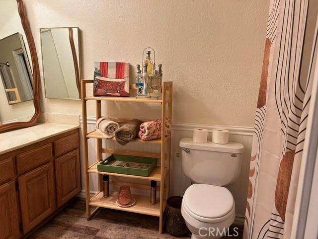 494 Delle Dr, Crestline, CA 92325 - bathroom featuring vanity, toilet, a wainscoted wall, and wood finished floors