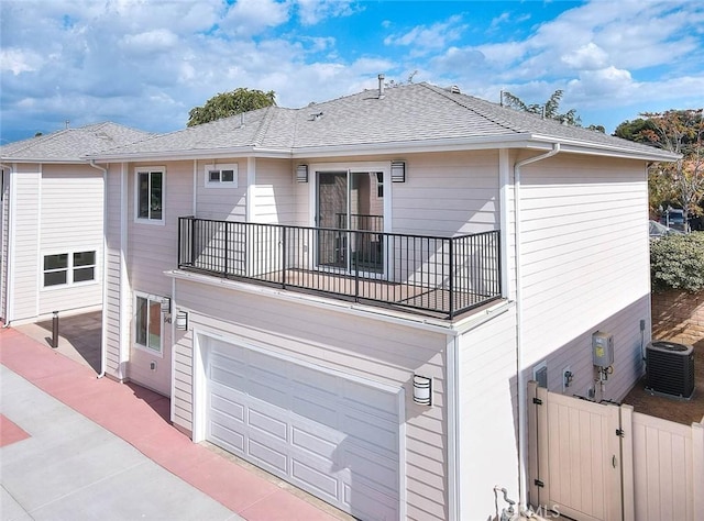 rear view of property with a balcony, a garage, and central air condition unit