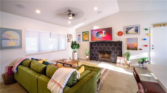 living room with vaulted ceiling, ceiling fan, and a tiled fireplace