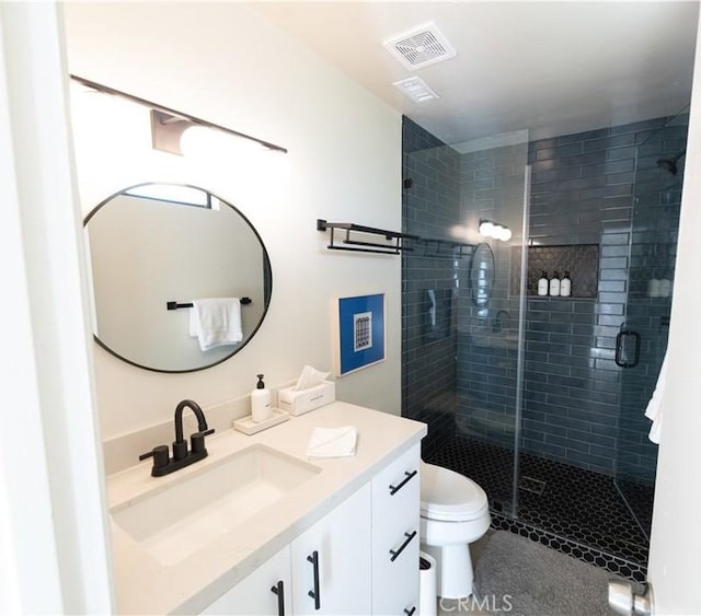 bathroom featuring a shower with door, vanity, and toilet