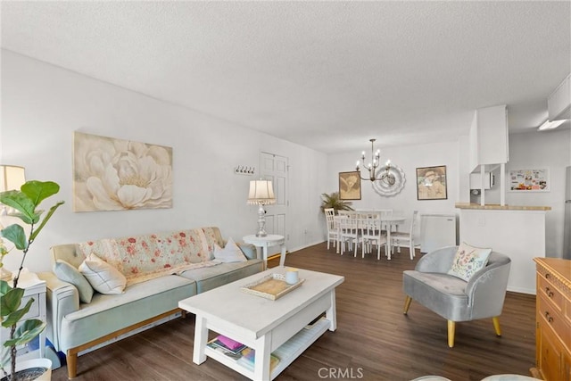 living room featuring a textured ceiling, dark wood-type flooring, and a notable chandelier