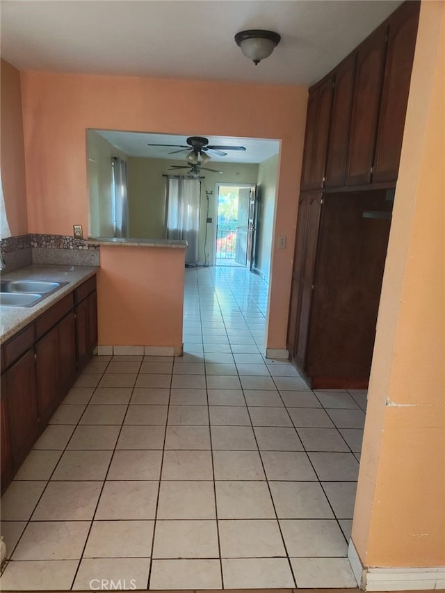 kitchen with kitchen peninsula, ceiling fan, light tile patterned floors, and sink