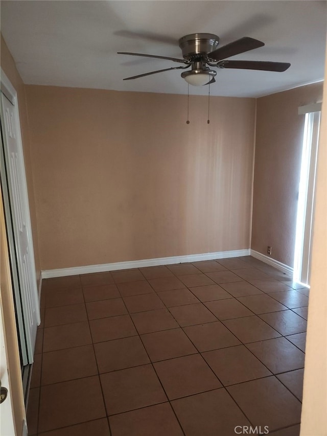 unfurnished room with dark tile patterned floors and ceiling fan