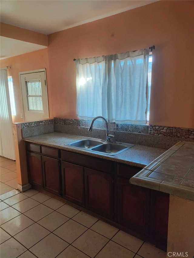 kitchen featuring dark brown cabinetry, sink, and light tile patterned floors