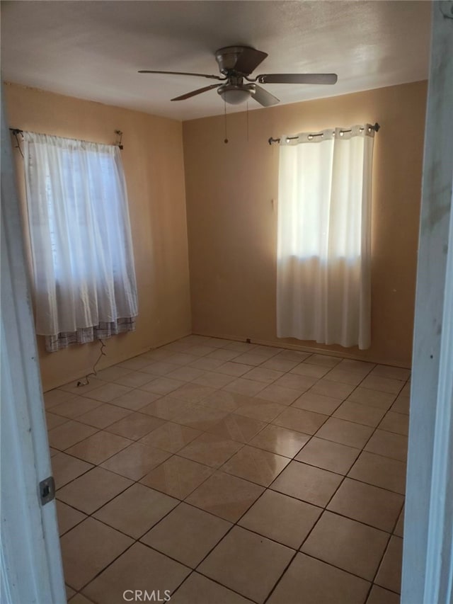 tiled spare room featuring ceiling fan