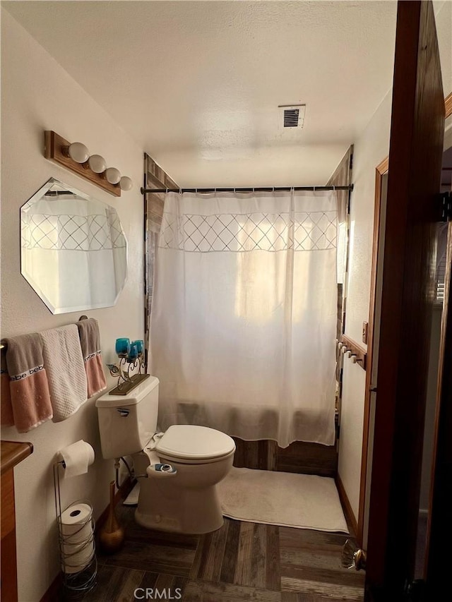 bathroom with shower / bath combo with shower curtain, hardwood / wood-style floors, and toilet