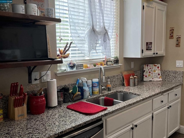 kitchen with white cabinets, light stone counters, dishwasher, and sink