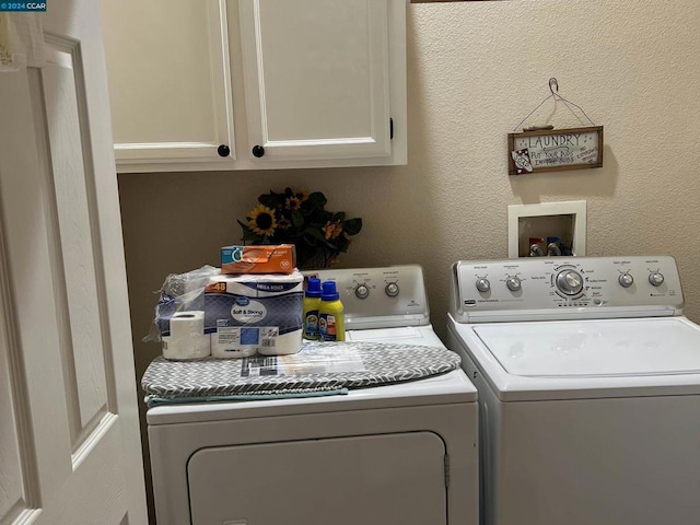 clothes washing area featuring washer and clothes dryer and cabinets