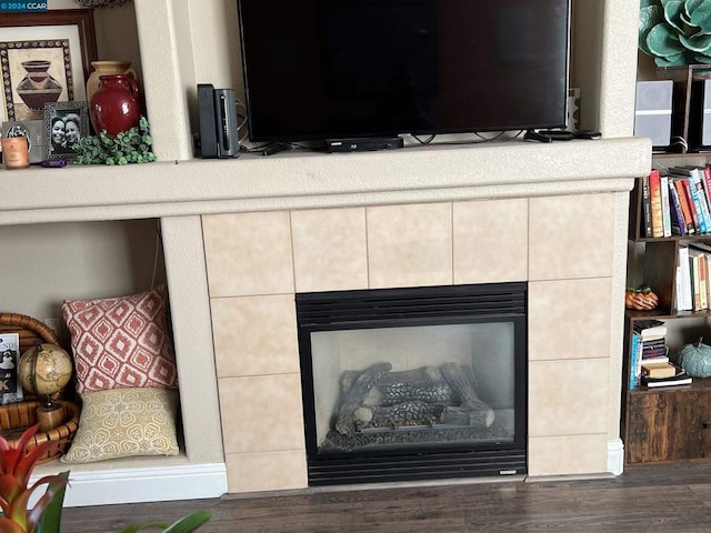 details with hardwood / wood-style flooring and a tiled fireplace