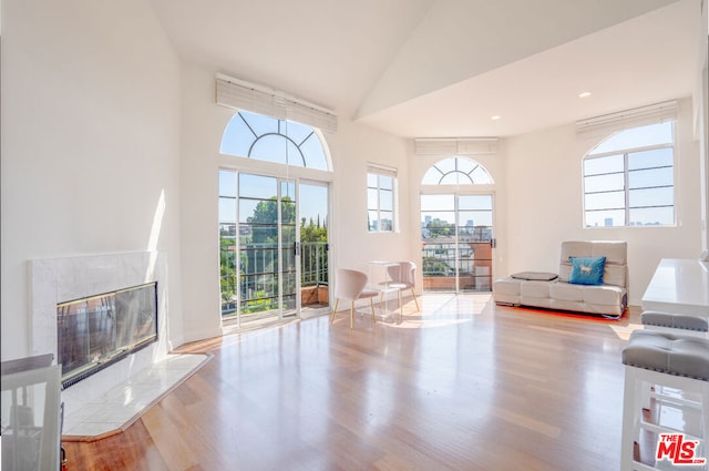 unfurnished living room featuring light wood-type flooring, a healthy amount of sunlight, and a tiled fireplace