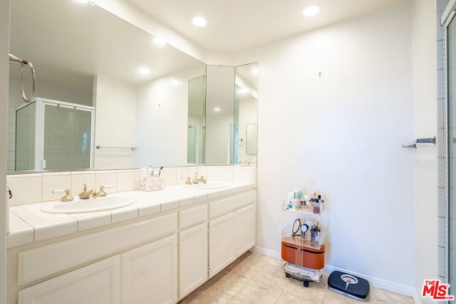 bathroom with tile patterned flooring, vanity, and walk in shower