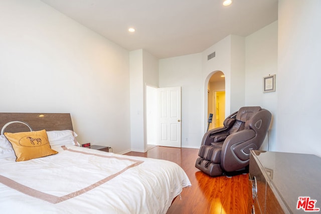 bedroom featuring hardwood / wood-style floors and a high ceiling