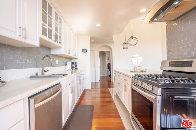 kitchen with wood-type flooring, appliances with stainless steel finishes, white cabinetry, and exhaust hood