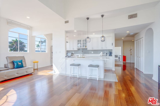 kitchen with white cabinetry, tasteful backsplash, light hardwood / wood-style flooring, kitchen peninsula, and pendant lighting