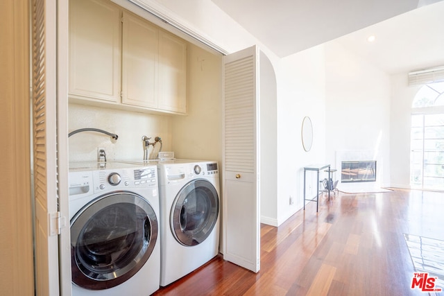 washroom featuring hardwood / wood-style floors, cabinets, and washing machine and clothes dryer