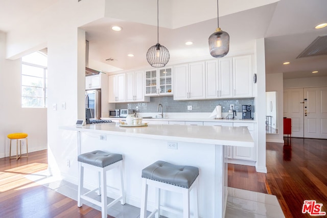 kitchen with hardwood / wood-style floors, backsplash, white cabinetry, and stainless steel appliances