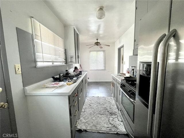 kitchen featuring dark tile patterned flooring, ceiling fan, gray cabinets, and stainless steel appliances