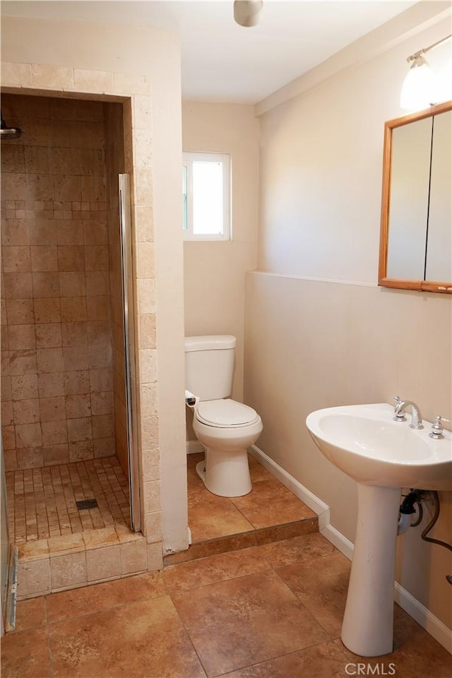 bathroom featuring toilet, sink, and a tile shower