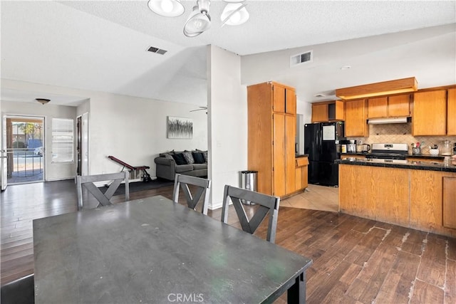 dining area with a textured ceiling, ceiling fan, lofted ceiling, and dark wood-type flooring