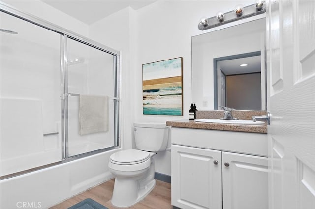 full bathroom with shower / bath combination with glass door, hardwood / wood-style floors, vanity, and toilet