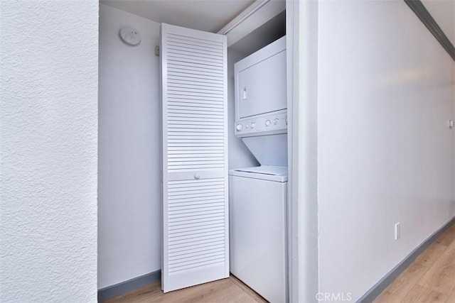 clothes washing area with light wood-type flooring and stacked washing maching and dryer