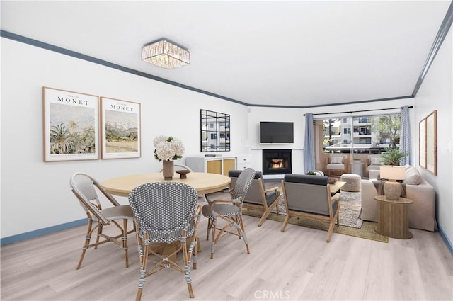 dining space with light wood-type flooring and crown molding