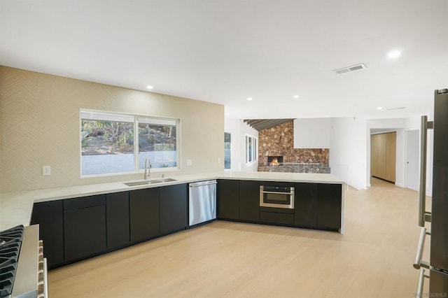 kitchen featuring kitchen peninsula, sink, stainless steel appliances, and light hardwood / wood-style flooring