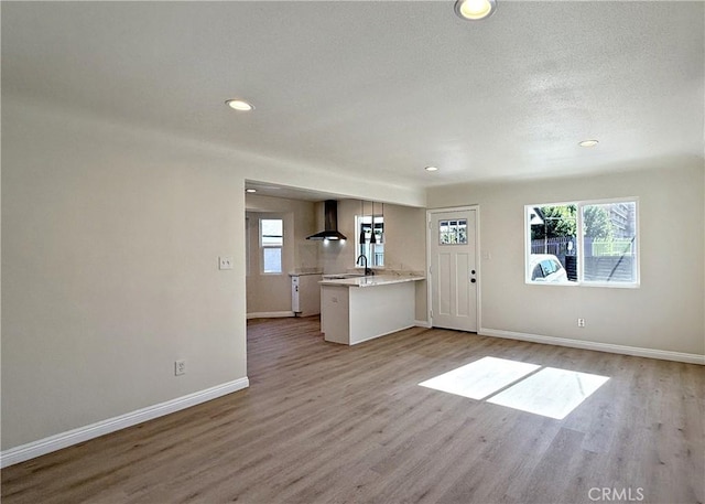 unfurnished living room featuring light hardwood / wood-style floors and a textured ceiling