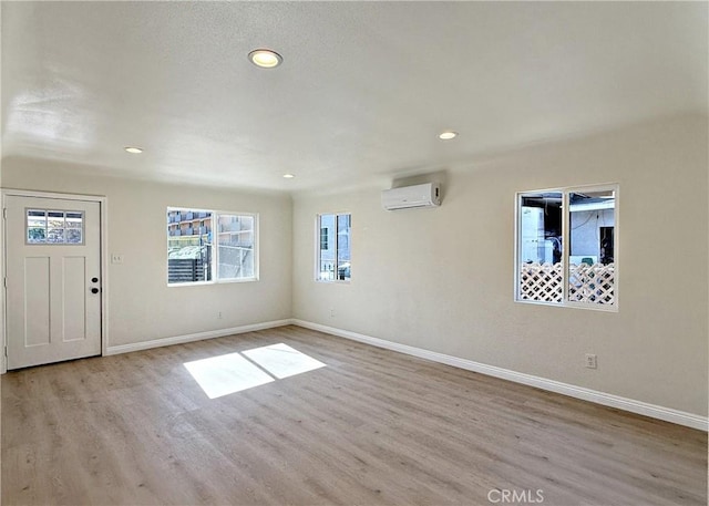 interior space with a wall mounted AC and light hardwood / wood-style flooring