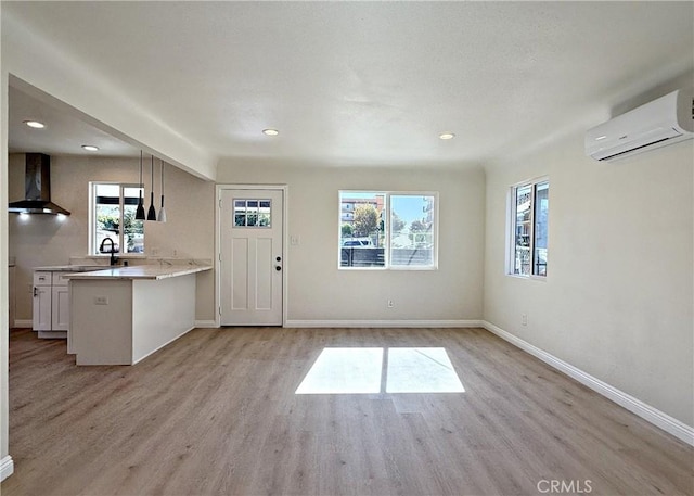 interior space with sink, a wall unit AC, and light hardwood / wood-style flooring