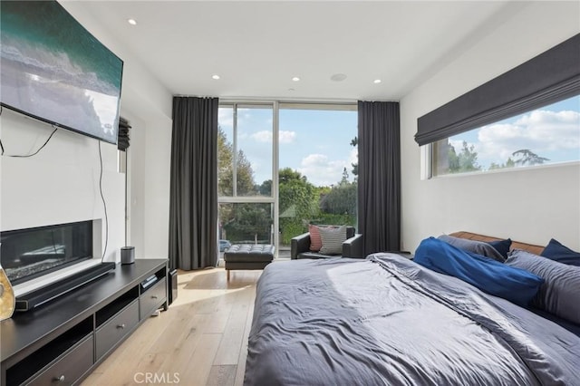 bedroom featuring a wall of windows and light wood-type flooring