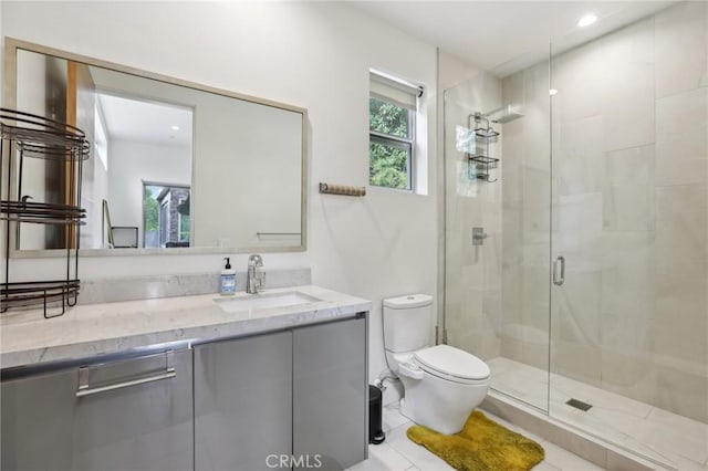 bathroom featuring vanity, a shower with shower door, tile patterned floors, and toilet