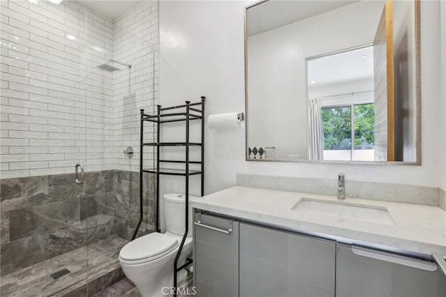 bathroom with a shower with door, vanity, and toilet