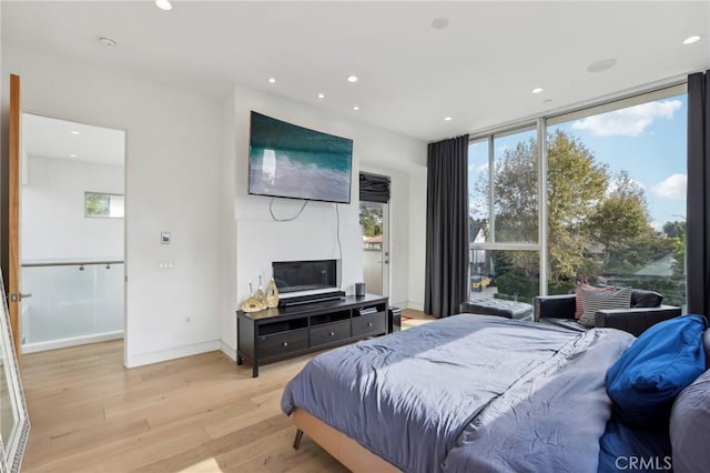 bedroom featuring a wall of windows and light hardwood / wood-style flooring